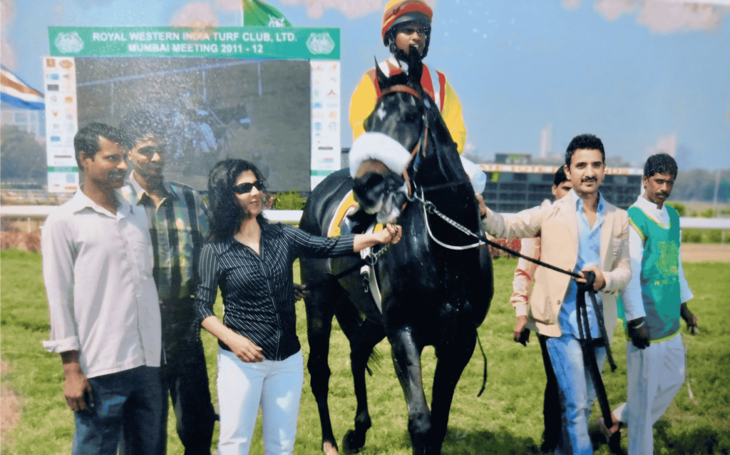 Sudheer Chauhan at Royal Western India Turf Club, Mumbai Meeting 2011–12, celebrating with his horse and team after a race victory, featuring the jockey mounted on the horse and supporters standing around.